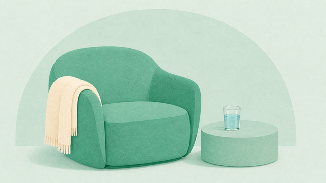 Soft green therapy chair with a folded blanket and water glass nearby.